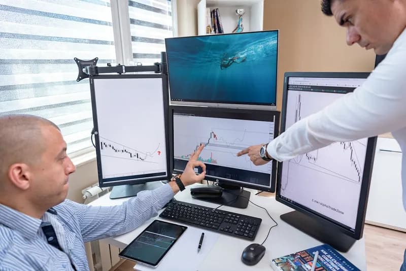 Professionnels analysant des graphiques de performance sur un écran